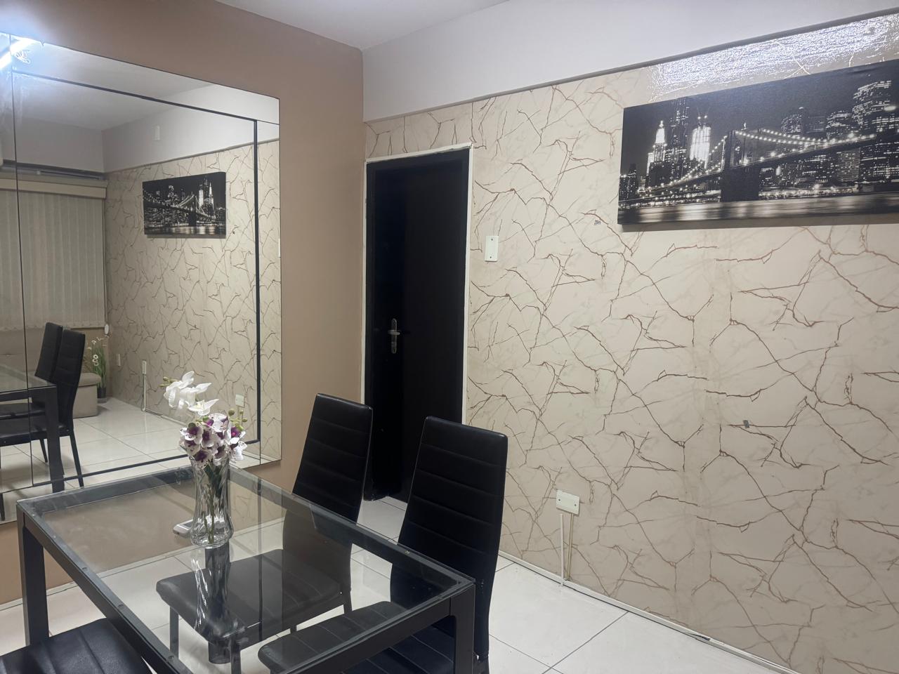 Ambiente com mesa de vidro, cadeiras, espelho e quadro na parede